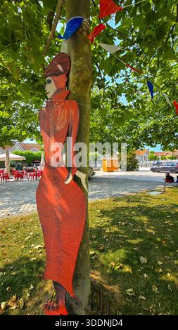 Juni 2025. Soulac-sur-Mer, Aquitaine, Frankreich. Ein grüner Park in einer Stadt mit einer geschnitzten Figur einer Frau in einem Vintage-Kleid im Vordergrund. Soulac 1 Stockfoto