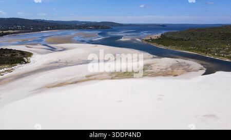 Erleben Sie die ruhige Schönheit der Sanddünen, die auf einen ruhigen Fluss treffen und die Weite der Natur und die friedliche Landschaft zeigen. Stockfoto