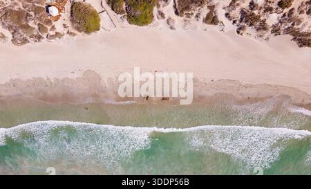 Aus der Vogelperspektive ist ein ruhiger Strand mit sanften Wellen, Sanddünen und ruhigen Gewässern zu sehen, der die Schönheit und den Frieden der Natur verkörpert. Stockfoto