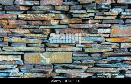 Gemalter Steinsteinmauerhintergrund, rustikale alte Grunge-Textur, farbenfrohe Vintage-ländliche Dekoration, Außenzaun Stockfoto