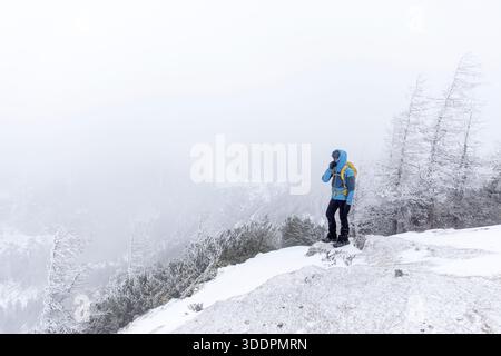 Einheimischer Mann auf Wandertour zum Vrsic Pass in den julischen alpen im triglav Nationalpark in slowenien, verschneite Landschaft nach Schneefall im Winter, kalt, nebelig Stockfoto