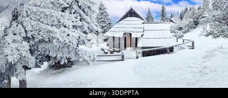 Winterlandschaft. Traditionelle, von tiefem Schnee bedeckte Holzhütten in den slowenischen Alpen. Authentisches Dorf in Velika Planina. Slowenisches Kulturerbe Stockfoto