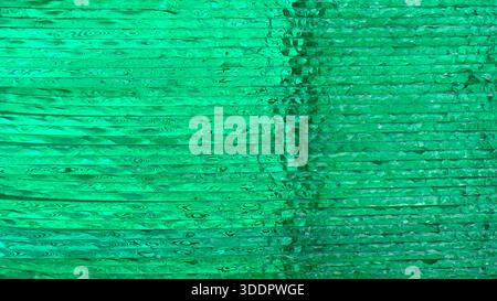Gestapelte transparente grüne Glasplatten bilden einen abstrakten Hintergrund mit welligen Mustern Stockfoto