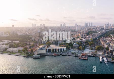 Ein faszinierender Blick aus der Luft fängt eine weitläufige Stadtlandschaft mit moderner Architektur, üppigem Grün und einer lebhaften Uferpromenade voller Aktivität ein. Ist Stockfoto