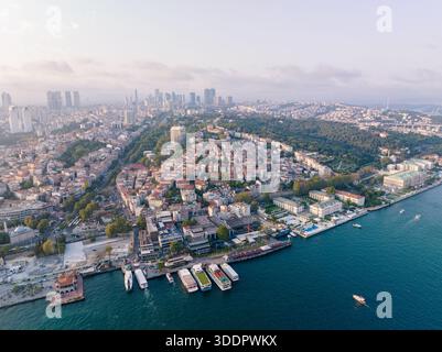 Ein faszinierender Blick aus der Luft fängt eine weitläufige Stadtlandschaft mit moderner Architektur, üppigem Grün und einer lebhaften Uferpromenade voller Aktivität ein. Ist Stockfoto