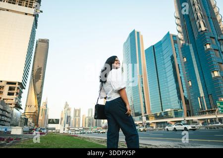 Selbstbewusste Unternehmerin in Dubai mit Blick auf den Burj Khalifa und die Skyline von Dubai Stockfoto
