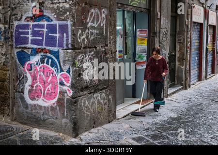 Eine Frau, die die Straße vor ihrem Geschäft sauber fegt, Centro Storico (historisches Zentrum), Neapel, Kampanien, Italien Stockfoto