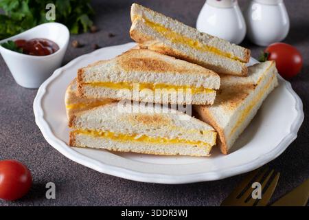 In der Pfanne gebratene Sandwiches mit Ei und Käse, serviert mit Tomatensauce zum Frühstück auf weißem Teller Stockfoto