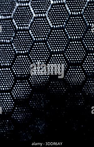 Nahaufnahme aus dunkelblauem Synthetik-Gewebe mit sechseckigem Netzmuster. Abstrakter industrieller Textil-Hintergrund für Technologie- und Sportdesign. Stockfoto