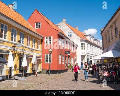 Leute, die in der Kopfsteinpflasterstraße Adelgade in der Altstadt von Ebeltoft, Jütland, Dänemark einkaufen Stockfoto