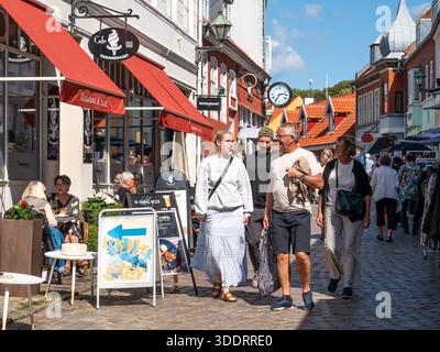 Leute schlendern entlang der kopfsteingepflasterten Einkaufsstraße Adelgade in der Altstadt von Ebeltoft, Jütland, Dänemark Stockfoto