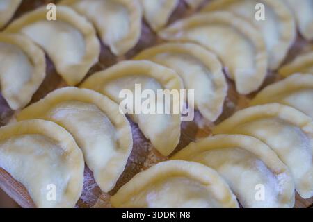 Teigknödel sind ordentlich auf einer Holzfläche angeordnet. Sie können in einer Küche zubereitet werden. Stockfoto