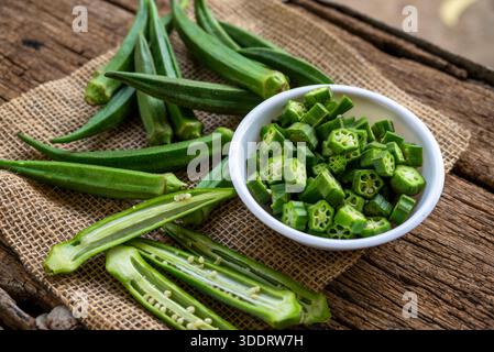 Farm frische, rohe Okra-Scheiben auf hölzernem, rustikalem Schneidebrett. Nahaufnahme von Lady Fingers oder Okra über hölzernem Hintergrund. Stockfoto