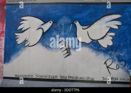 BERLIN-Deutschland-17. April 2025,Wandgemälde mit zwei Tauben, die Stacheldraht auf dem erhaltenen Abschnitt der Berliner Mauer auseinanderziehen und Frieden und Frieden symbolisieren Stockfoto