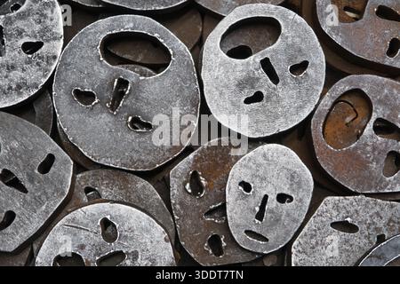 BERLIN-Deutschland-18. April 2025, Nahaufnahme von sich überlappenden, kreisförmigen Metallausschnitten mit Löchern in Form abstrakter Augen, Nasen und Mout Stockfoto