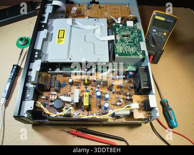 Handprüfung der elektronischen Leiterplatte mit Multimeter; Nahaufnahme der Hände des Technikers mit Hilfe eines Multimeters zur Diagnose oder Reparatur komplexer elektronischer Schaltungen Stockfoto