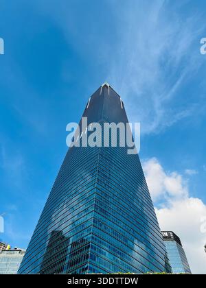 Flacher Blick auf einen modernen Wolkenkratzer mit reflektierender Glasfassade. Stockfoto