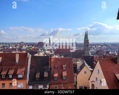 28.09.2025 Nürnberg, Deutschland: Das weitläufige Stadtbild Nürnbergs mit rot gekachelten Dächern, historischen Kirchtürmen und einem hellblauen Himmel Stockfoto