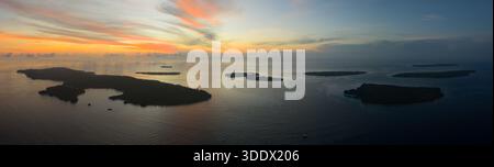 Ein beschaulicher und farbenfroher Sonnenaufgang bildet die Fam Islands in Raja Ampat, Indonesien. Dieses tropische Gebiet bietet eine spektakuläre Meeresvielfalt. Stockfoto