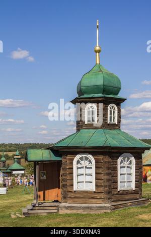 Antike hölzerne orthodoxe Kapelle in Nizhnyaya Sinyachikha, Ural, Russland. Traditionelle russische religiöse Architektur unter blauem Sommerhimmel Stockfoto