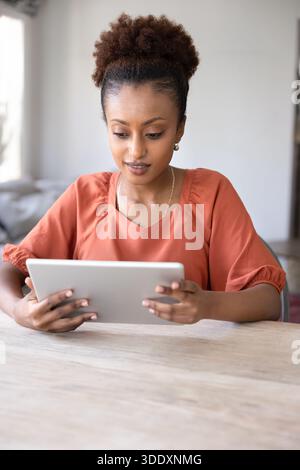 Positive junge afroamerikanische Frau, die Videoinhalte auf dem Tablet ansieht Stockfoto