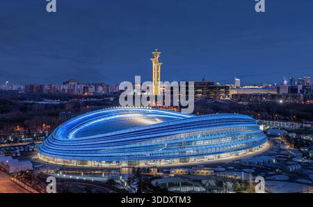 Beleuchtete Peking National Speed Skating Oval und Olympiaturm bei Nacht, die moderne Architektur und die Skyline der Stadt hervorheben. Stockfoto