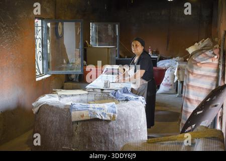 Eine ältere Frau arbeitet in einer traditionellen, rustikalen Bäckerei mit Brot und Backzubehör, Bäckerei in Badiauri, Kakheti Region, Georgien Stockfoto