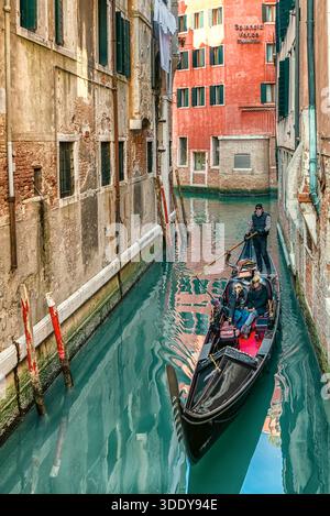 Venedig, Italien - 11. Februar 2018: Gondelfahrt durch einen engen Kanal zwischen alten Wohnhäusern im historischen Zentrum von Venedig Stockfoto