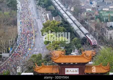 (260104) -- PEKING, 4. Januar 2025 (Xinhua) -- die Teilnehmer laufen während des Wuhan-Marathons in Wuhan, der Provinz Hubei im Zentrum Chinas, am 23. März 2025 vorbei an Huanghelou oder dem Gelben Kranturm. (Xinhua/Wu Zhizun) Stockfoto