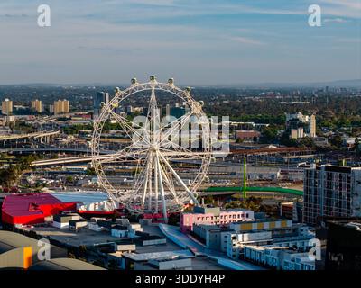 Ein Blick aus der Vogelperspektive zeigt das Melbourne Star Ferris Rad, umgeben von ausgedehnten Straßennetzen und vielfältiger Stadtarchitektur an klaren Tagen. Stockfoto