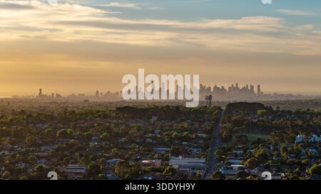 Ein erhöhter Blick fängt eine riesige urbane Landschaft ein, dicht mit Häusern und Bäumen, die sich bis zu einer entfernten, trüben Skyline der Stadt erstreckt. Stockfoto