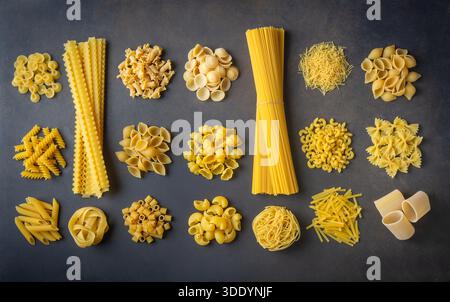 Komposition mit verschiedenen leckeren rohen Nudeln - italienische Nudeltapete, verschiedene Arten und Formen des Pasta-Layouts Stockfoto