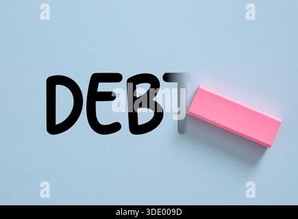 Radiergummi räumt das Wort SCHULDEN auf einem hellblauen Hintergrund, was die Lösung und Erleichterung finanzieller Probleme repräsentiert. Schuldenerlöschung. Stockfoto