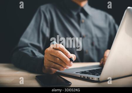 Nahaufnahme eines Mannes Hand in einer Pose, bereit, mit einem digitalen Stift zu signieren. Diese Geste ist ein deutliches Zeichen für ein Stockfoto