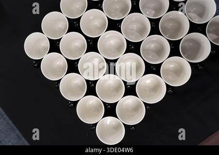 Weiße Becher in einem Rautenmuster auf schwarzer Oberfläche Stockfoto