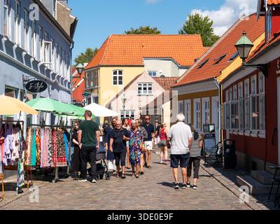 Leute, die in der Kopfsteinpflasterstraße Adelgade in der Altstadt von Ebeltoft, Jütland, Dänemark einkaufen Stockfoto