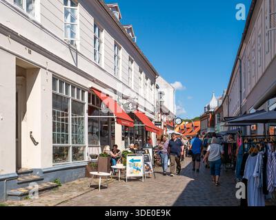 Straßencafé mit Spaziergängen und Einkaufen in der kopfsteingepflasterten Straße Adelgade in der Altstadt von Ebeltoft, Jütland, Dänemark Stockfoto