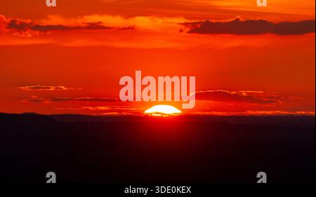 Ein lebhafter, rot-orange Sonnenuntergang über den Silhouetten der Chiltern Hills in England. Stockfoto