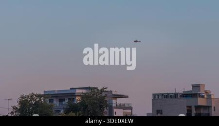 Vertikale Weitwinkelaufnahme auf Augenhöhe mit zeitgenössischen Wohngebäuden und einer Skyline am Hang unter einem riesigen blauen Himmel mit einem einsamen Hubschrauber Stockfoto