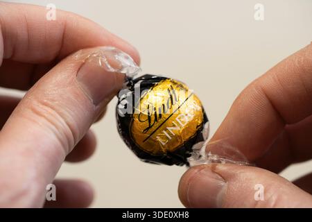 Mann hält Lindor Trüffel aus dunkler Schokolade von der Schweizer Chocolatier & Süßwarenfirma Lindt. UK. Konzept: Kakaopreis, Lebenshaltungskosten Stockfoto