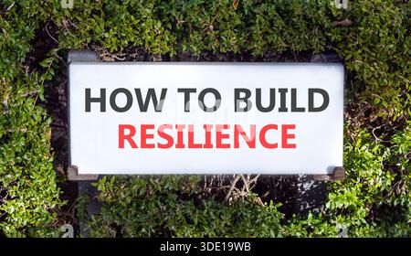 So erstellen Sie ein Resilienzsymbol. Konzeptworte wie man Widerstandsfähigkeit auf weißem, wunderschönem Straßenschild schafft. Wunderschöne grüne Bäume im Hintergrund. Geschäftsanweisungen Stockfoto