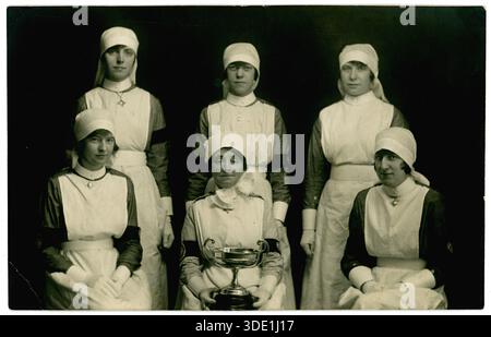 Die ursprüngliche Postkarte aus der Zeit der 1920er Jahre von einer Gruppe von Krankenschwestern in Uniform, sie wurden mit einer Trophäe überreicht, auf der Rückseite ist Stockport geschrieben und datiert 1925 - aus dem Studio von George Connard, 121 Oldham Rd Ashton-under-Lyne, Greater Manchester, England, Großbritannien Stockfoto