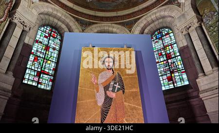 Ein großes Mosaik Christi steht im Inneren der Basilika Heiliges Herz. Buntglasfenster umgeben das Kunstwerk und schaffen eine bunte Kulisse Stockfoto