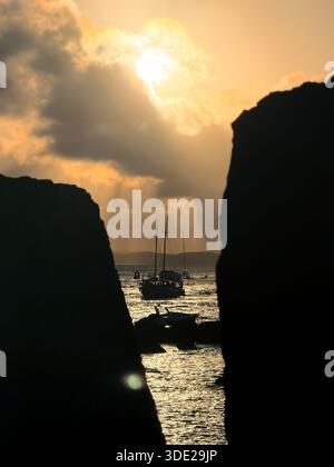 Goldener Sonnenuntergang mit Sonnenstrahlen, die durch Wolken über dem Ozean brechen. Eingerahmt von der Steinmauer des Morro de São Paulo Forts in Bahia, Brasilien Stockfoto