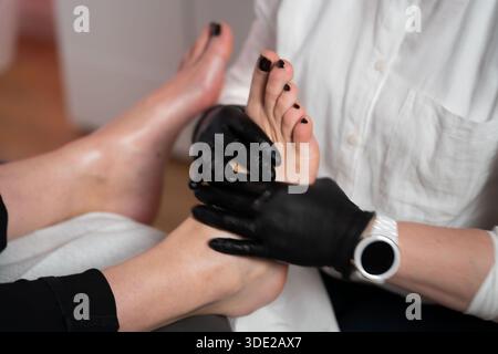 Nahaufnahme der professionellen Fusspflege und -Massage. Handschuhe behandeln den Fuß im Schönheitssalon. Stockfoto