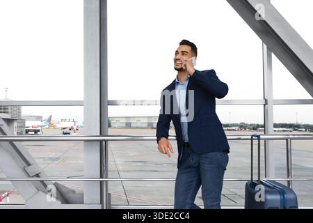 Schöner Junger Mann Aus Dem Nahen Osten, Der Am Flughafen Auf Dem Mobiltelefon Spricht Stockfoto