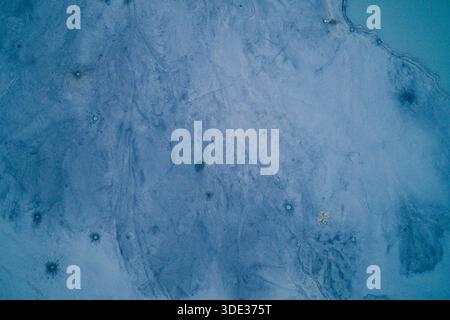 Faszinierende Draufsicht auf eine gefrorene Oberfläche mit tiefblauen Tönen und komplizierten weißen Frostdetails. Das kalte abstrakte Muster schafft einen erfrischenden Winterhintergrund, ideal für Design-Overlays, Tapeten und kreative Kunst. Stockfoto