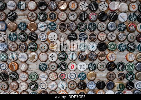 Shanghai, China - 24. April 2025 runde Flaschenverschlüsse, die in einem Gittermuster auf einer gewebten Strohmatte angeordnet sind. Kappen zeigen Anzeichen von Rost, abplatzendem Lack und Alter. Stockfoto