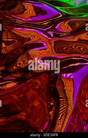 Ein lebendiges, abstraktes Foto, das eine faszinierende, farbenfrohe Kunst zum Gießen von Flüssigkeiten zeigt. Das Bild zeigt wirbelnde, fließende Muster in Neontönen Stockfoto