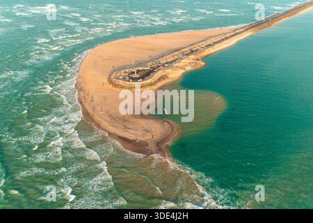 Aus der Vogelperspektive auf einen Sandstreifen, der vom türkisfarbenen Meer umgeben ist, mit Wellen, die sanft das Ufer küssen, einer Brücke, die sich zum Horizont erstreckt, Dhanuschkodi, Stockfoto